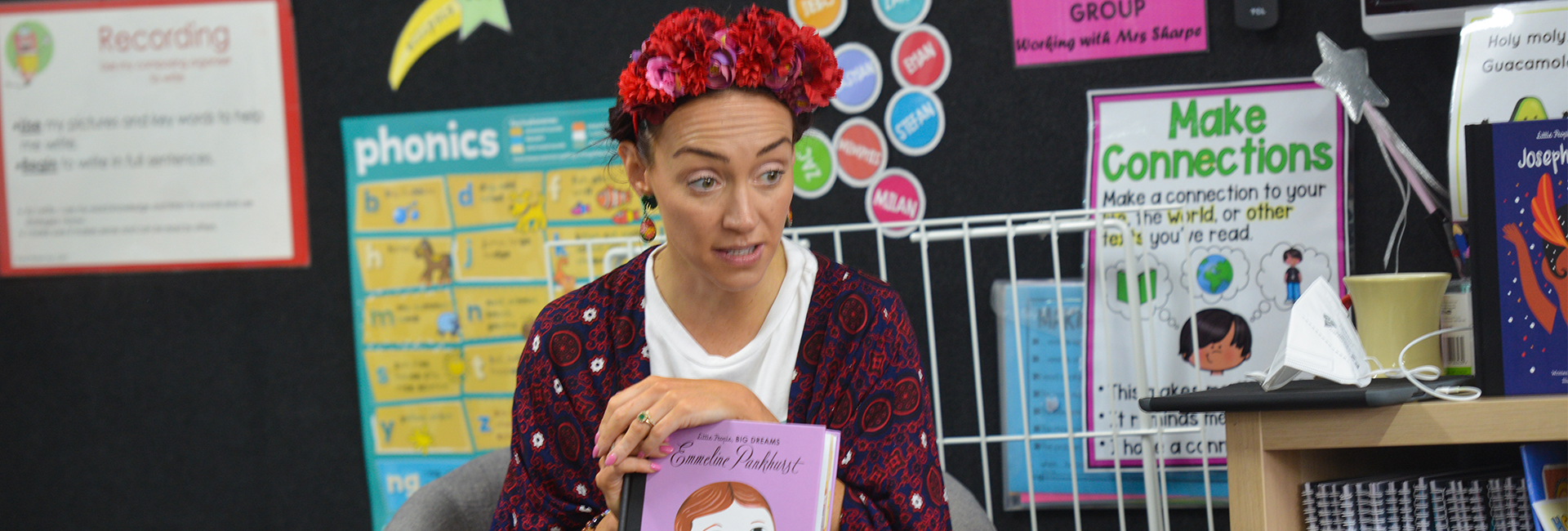 A Southern Cross Grammar teacher is dressed as Frida Kahlo. She has red flowers in her hair and is holding a book called Little People Big Dreams: Emmeline Pankhurst